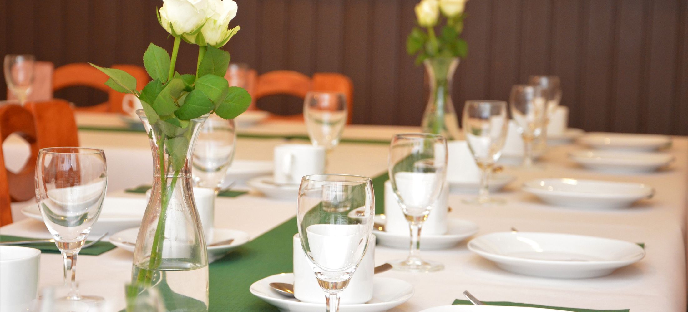 Gedeckter Tisch mit Gläsern und Blumenvasen